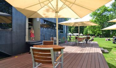 Terrasse mit Holzboden und -stühlen und Sonnenschirmen