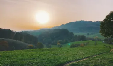 Blick über grüne Hügel bei Sonnenuntergang