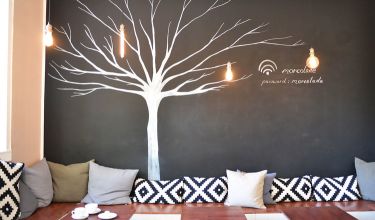 Rückwand des Cafés mit gemaltem Baum auf schwarzer Wand