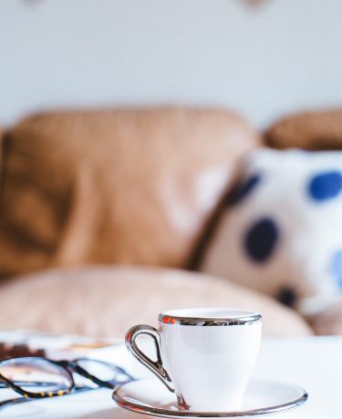 Eine Kaffeetasse und gemütliche Kissen daheim oder im Café