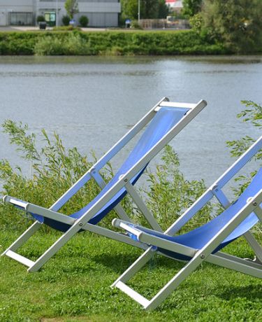 2 Liegestühle am grasgrünen Ufer