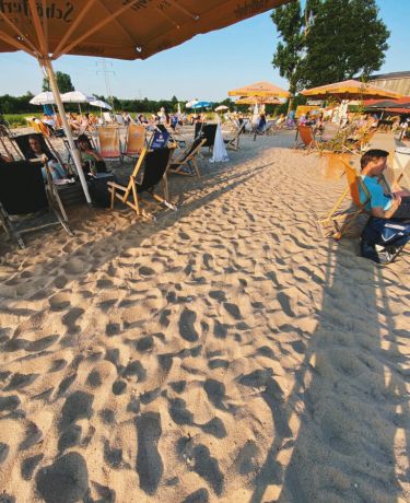 Sand mit Fußabdrücken, Liegestühle und Sonnenschirme am Niddastrand
